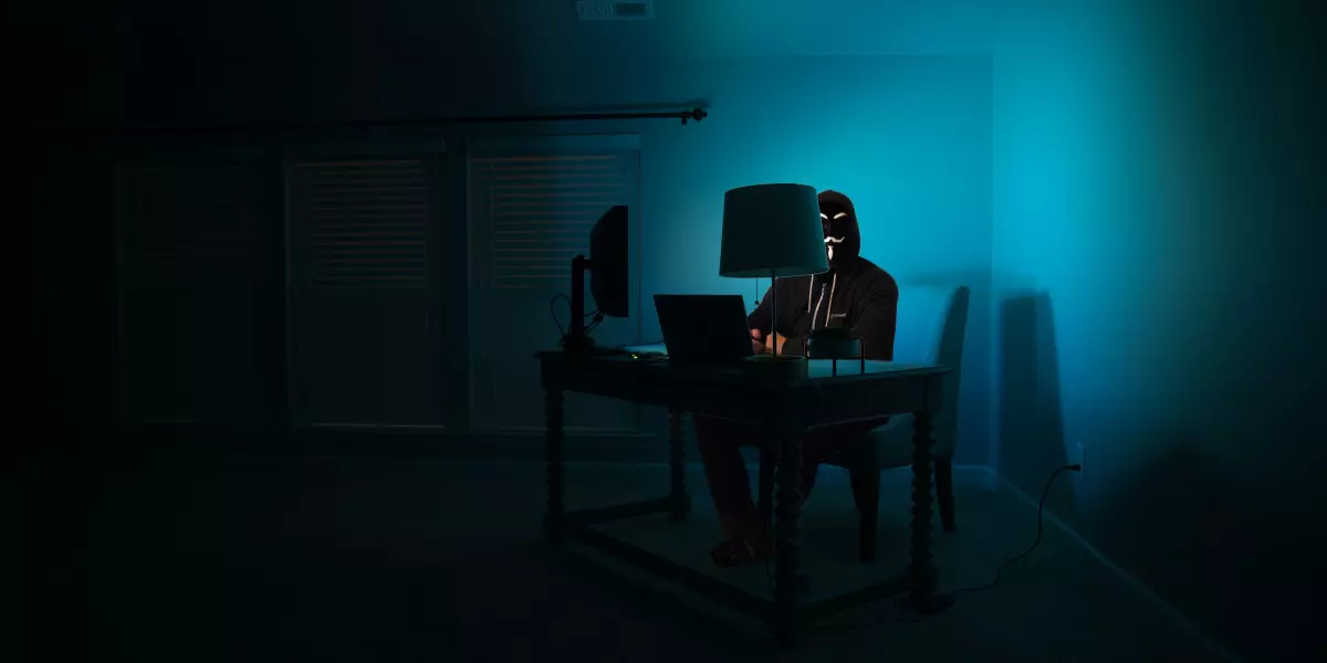 masked hacker behind a computer